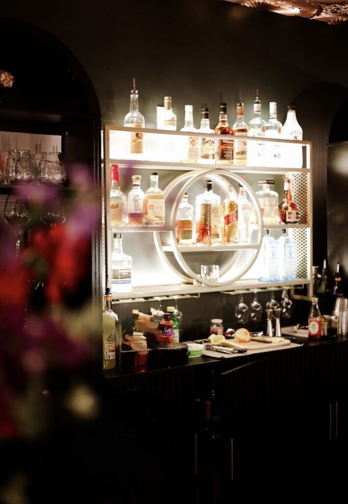 Backlit bar display seen past fresh flowers at The Event Vault