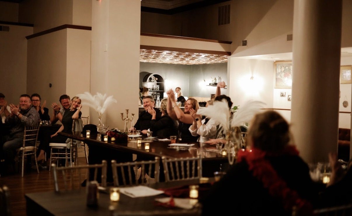 Guests applauding at a candlelit dinner event at The Event Vault