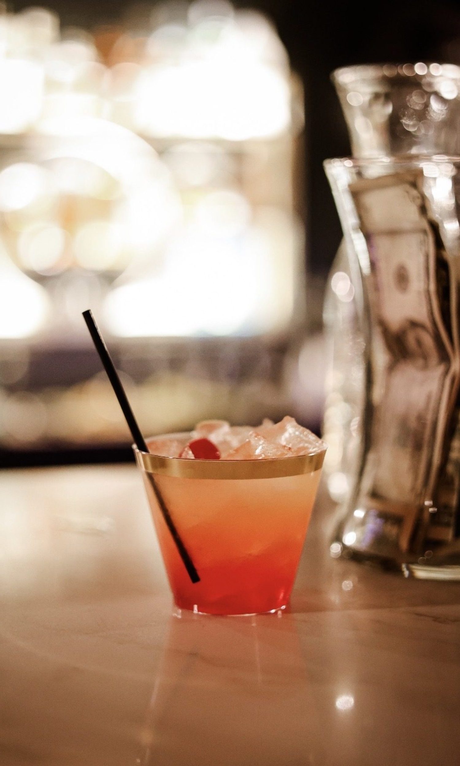Craft cocktail with cherry garnish in a gold-rimmed glass at The Event Vault bar