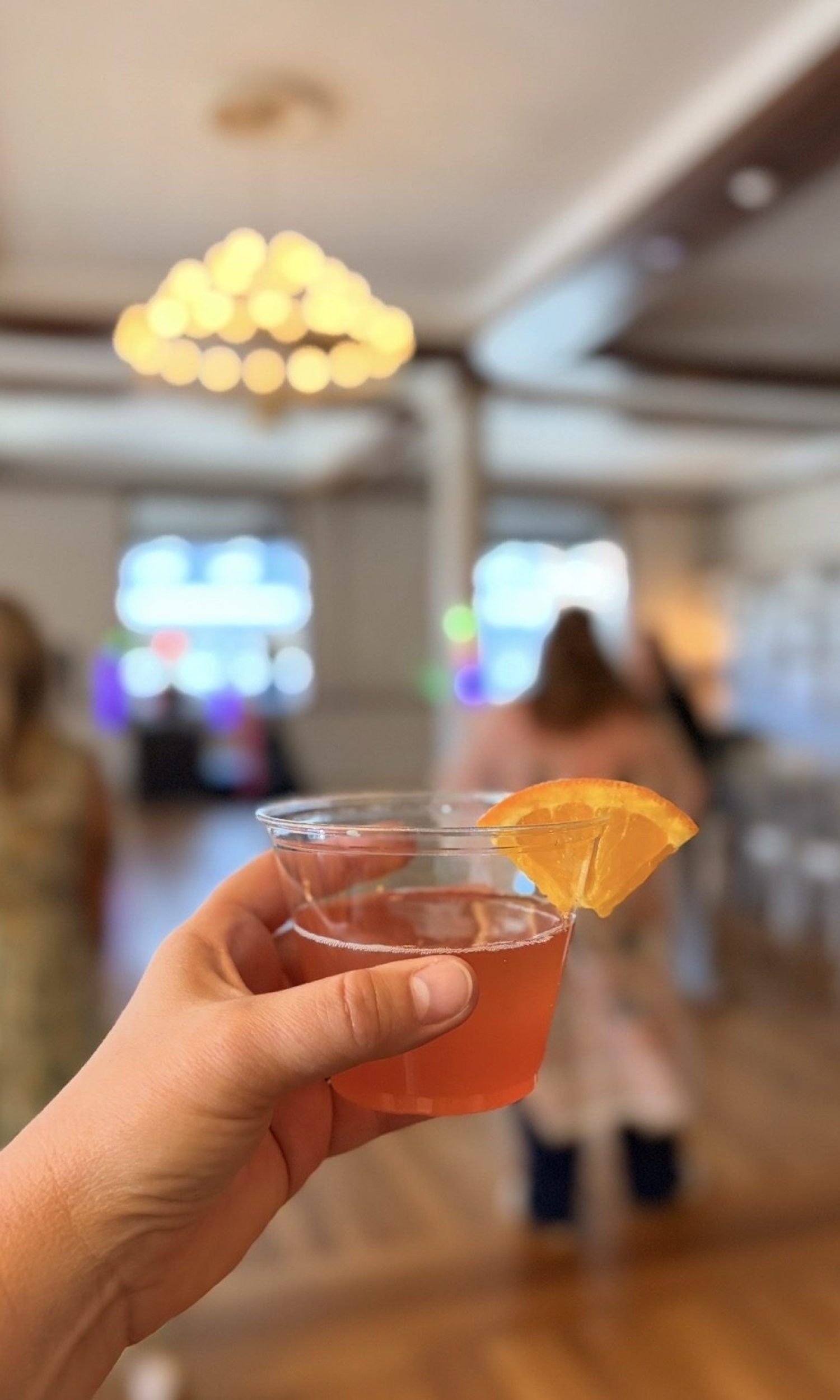 Guest raising a signature cocktail with an orange garnish at The Event Vault in Urbana, Ohio